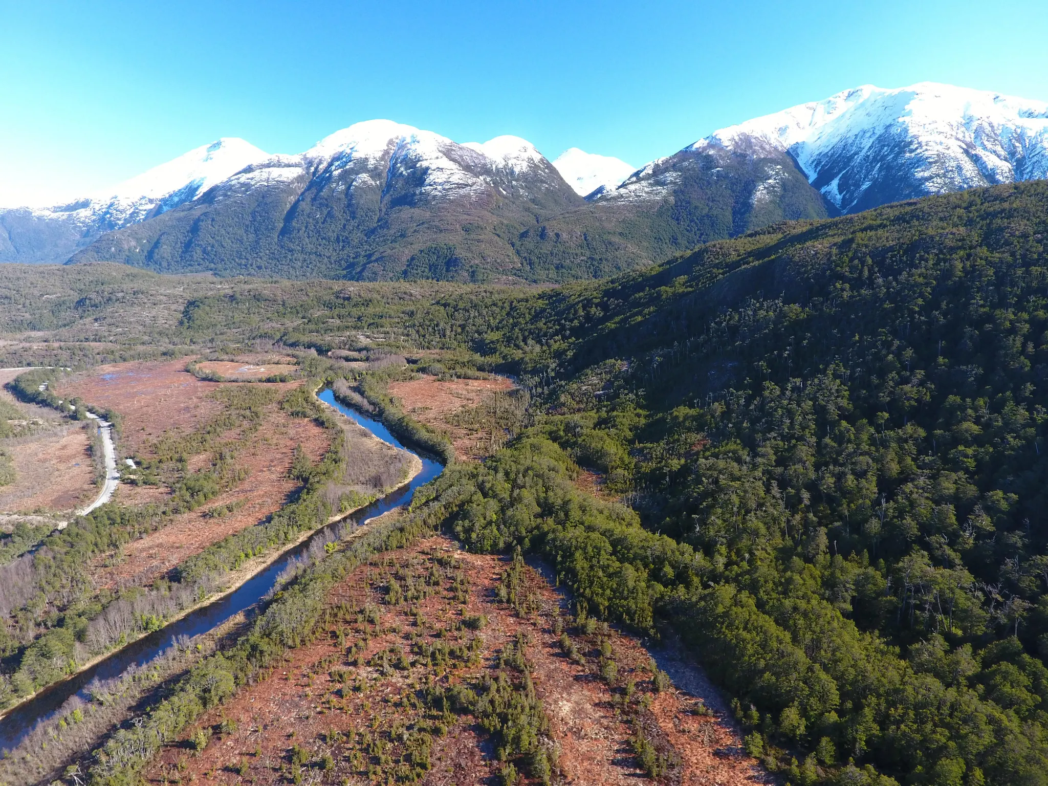 Vista aérea del Río Vargas entre bosque y vegetación baja, con la cordillera al fondo